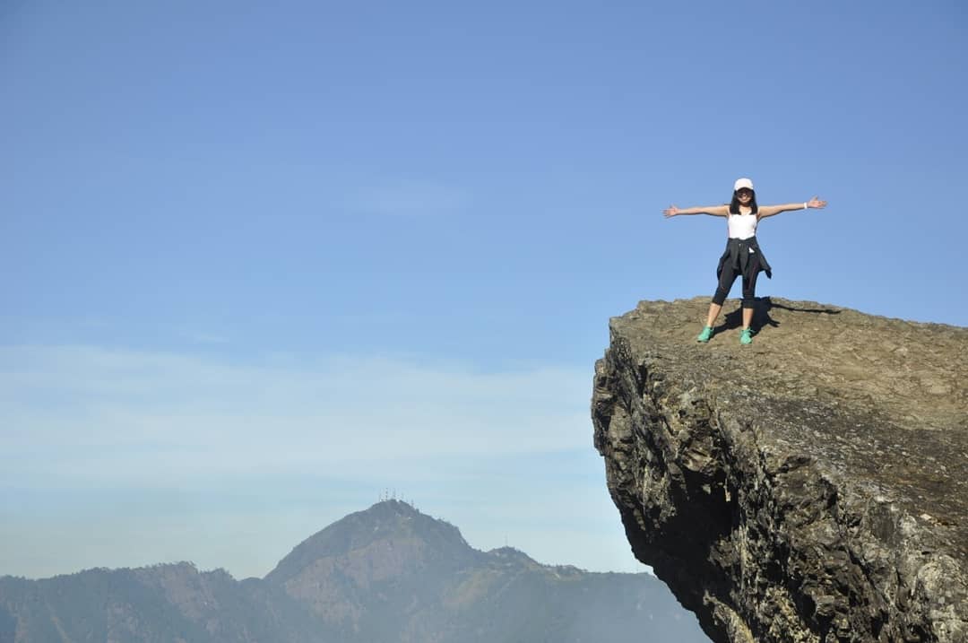 Pam standing at the edge of a dramatic cliff overlook