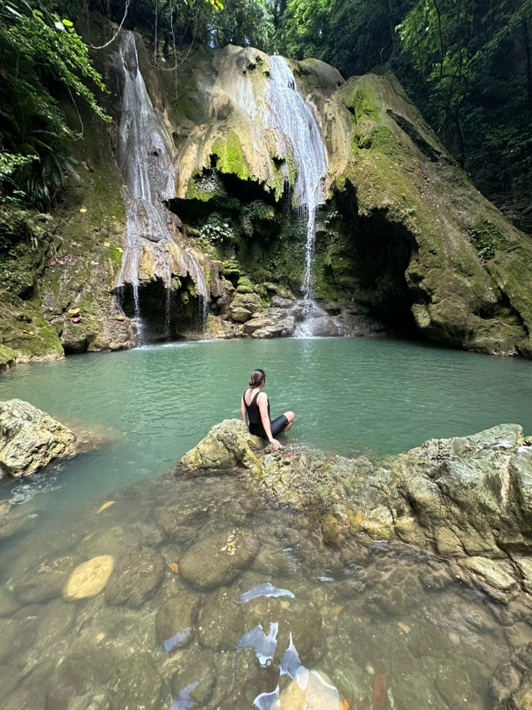 Pam sitting by a waterfall pool