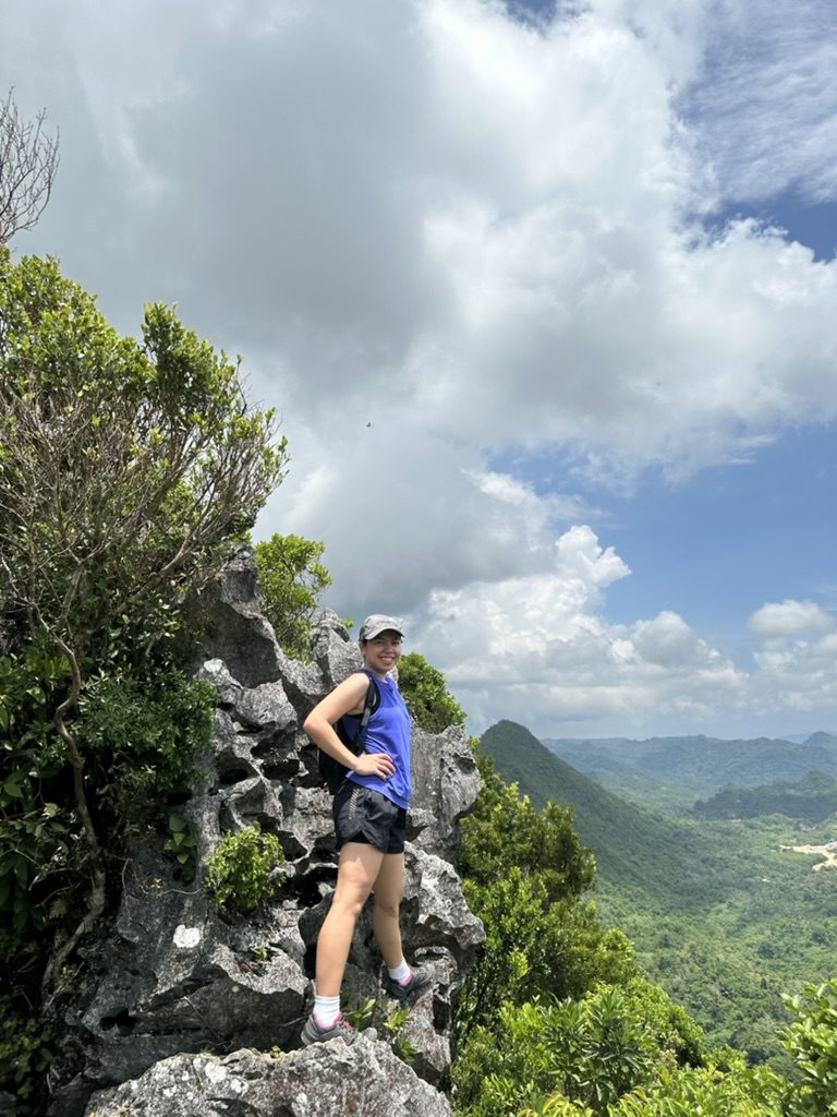 Pam smiling on a limestone cliff above a green valley