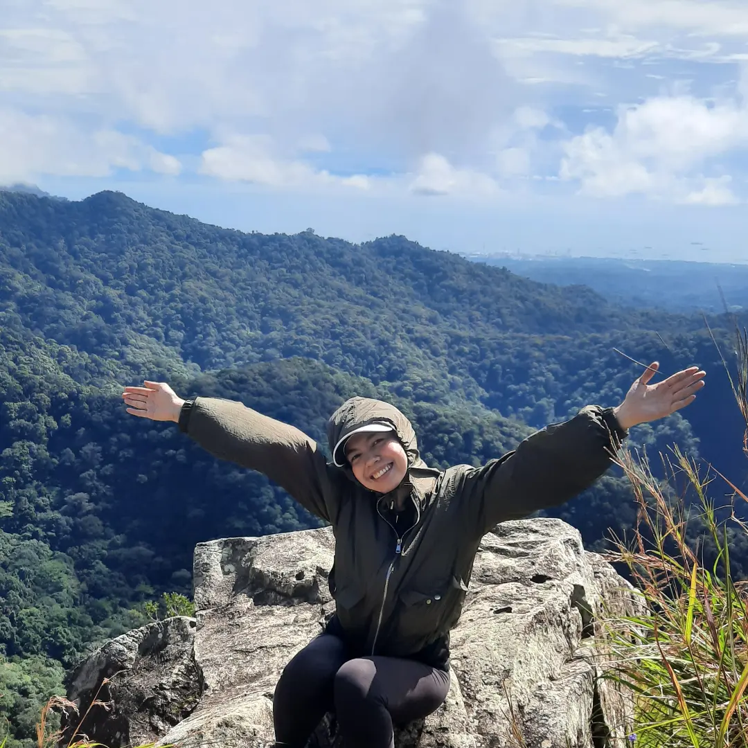 Pam with arms outstretched atop a misty summit